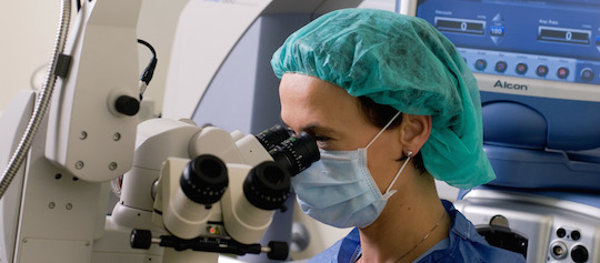 Eye doctor looking through microsope